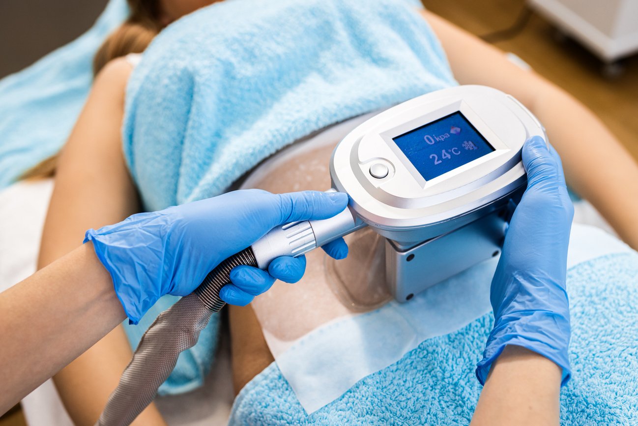 Beautician applying cryolipolysis treatment in beauty salon.